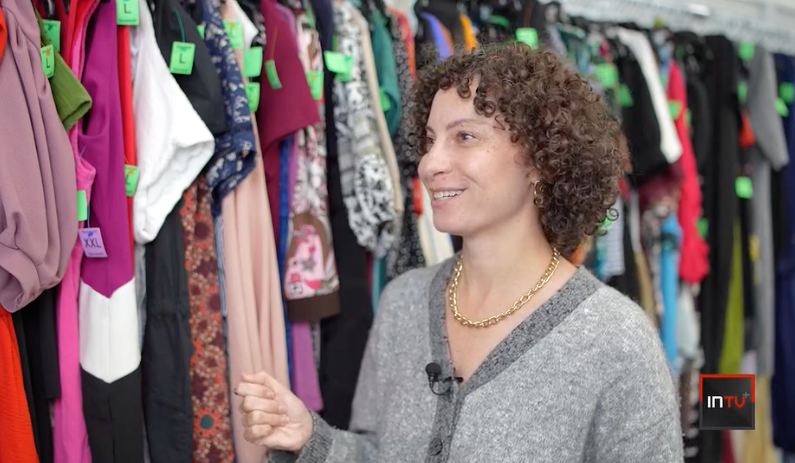 Stephanie speaking in front of a rack of clothes during the InvestigateTV+ interview