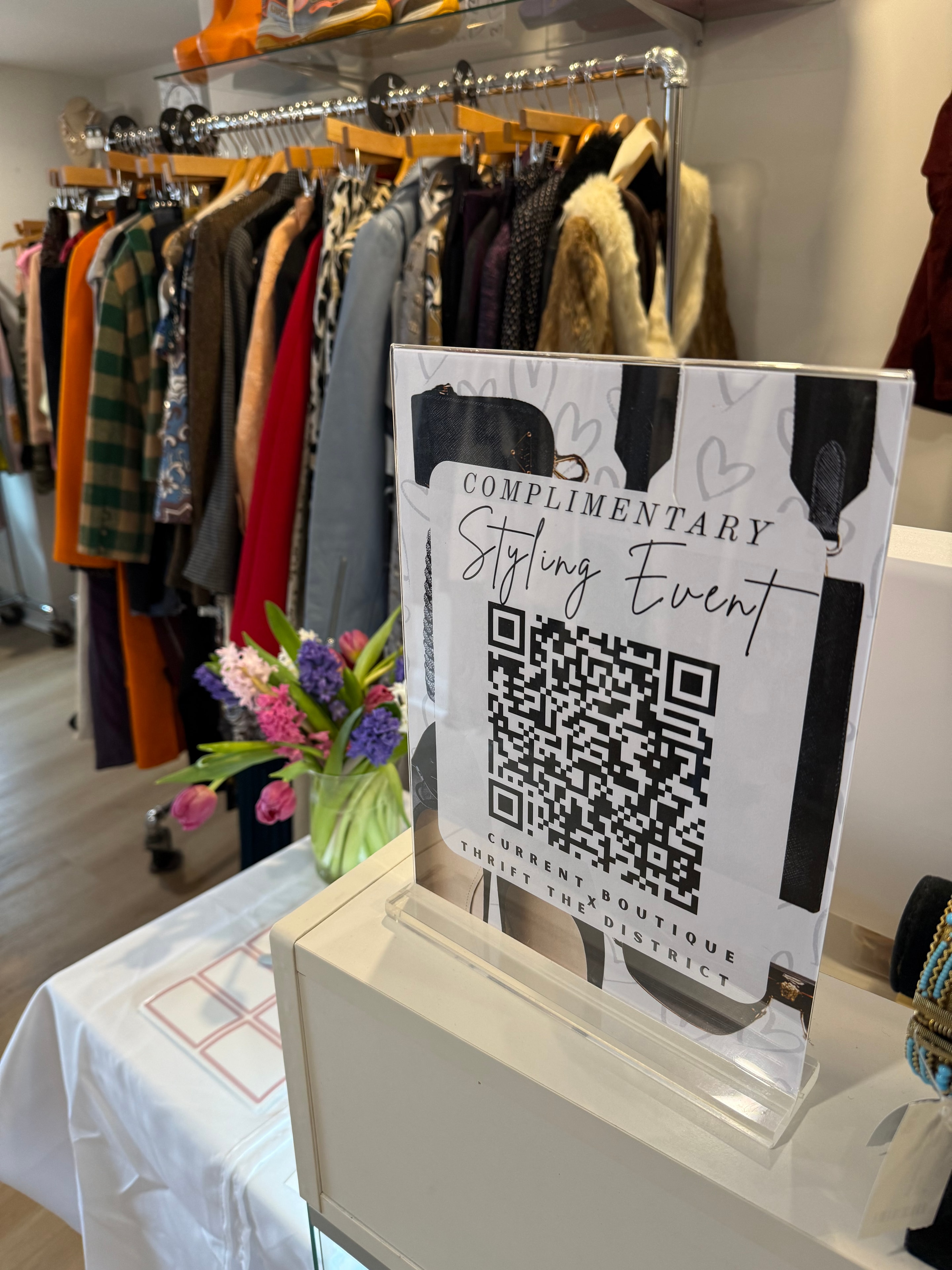 Clothing racks with colorful garments and a mirror reflection at Current Boutique Georgetown