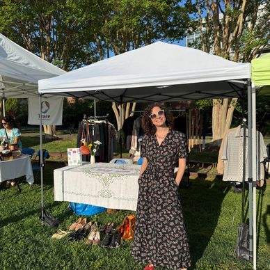 Woman in sunglasses standing under a white canopy at an outdoor market