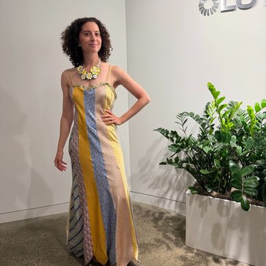 Woman in a colorful striped dress posing indoors near green plants